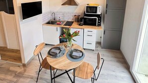 Une cuisine moderne avec des meubles en bois, un four à micro-ondes encastré et un coin repas avec une table dressée pour deux personnes.
