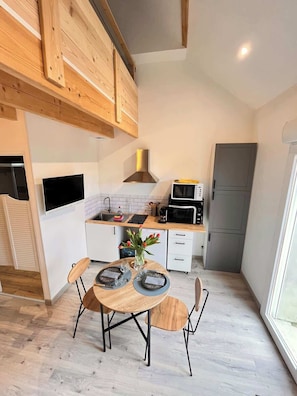 Una cocina moderna con armarios de madera, microondas integrado y comedor con mesa dispuesta para dos.