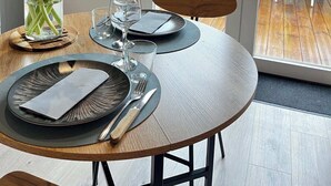 Une table à manger dressée avec des assiettes, des couverts et un vase de tulipes.