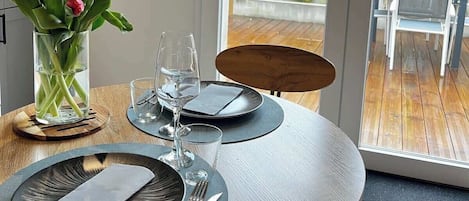 Una mesa de comedor dispuesta con platos, cubiertos y un jarrón de tulipanes.