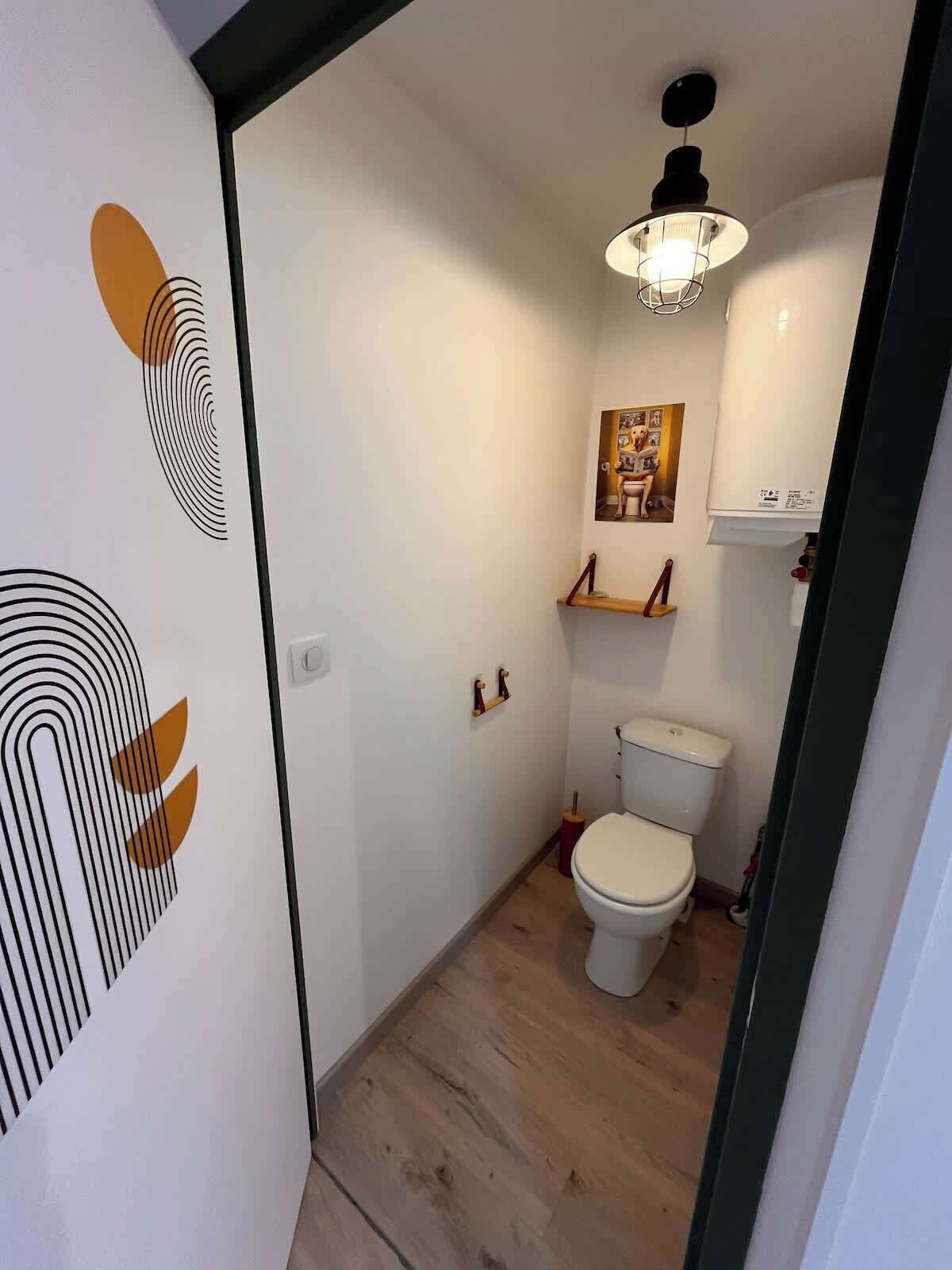 Een badkamer met toilet, douche en een plafondlamp.