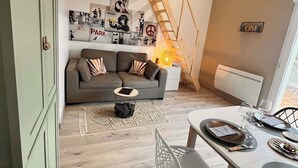 Una sala de estar moderna con sofá, mesa de centro y comedor con sillas y una mesa dispuesta para dos.
