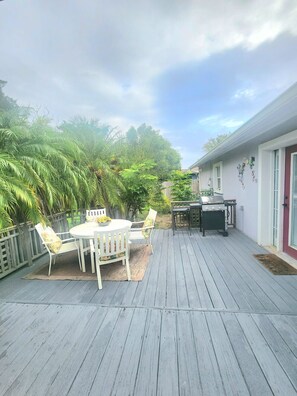 A wooden deck with a round table and chairs, a grill, and a wooden fence. - Palm Paradise 5 min to Downtown 5 min to the Beaches (St. Augustine)