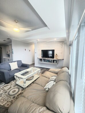 A living room with a sofa, a coffee table, and a TV mounted on a wall. - Coral Cove Cottage-Walk to Beach-Near Downtown (St. Augustine)