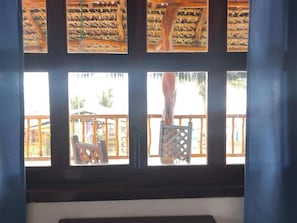 A room with a view of a wooden deck and a thatched roof structure outside.