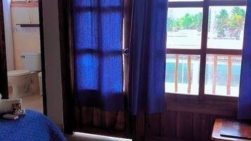Una habitación con cama, una mesita y una ventana con cortinas.