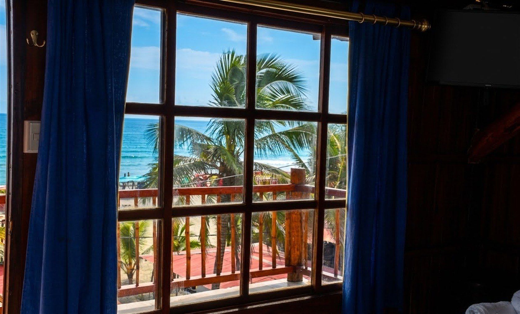 Una ventana con vistas a una playa y palmeras.