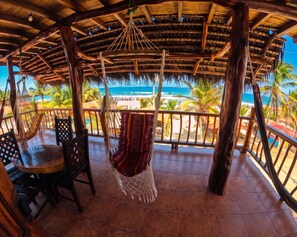 Un área de estar al aire libre, cubierta, con vistas a la playa y al océano.
