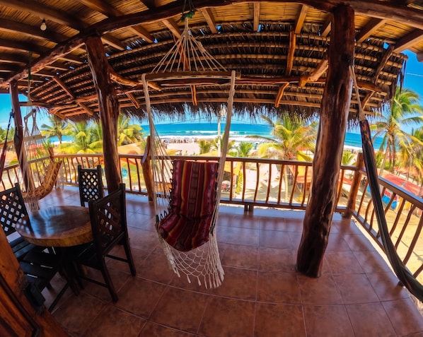 Un área de estar al aire libre, cubierta, con vistas a la playa y al océano.