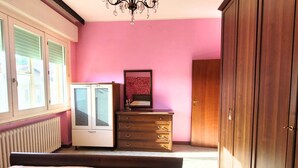 Ein Schlafzimmer mit Bett, Kommode, Spiegel und Kleiderschrank.