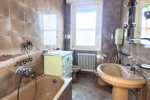 Ein Badezimmer mit Badewanne, Waschbecken, Toilette und Fenster.
