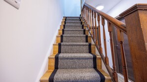 Un escalier avec une rampe en bois et des marches recouvertes de moquette.