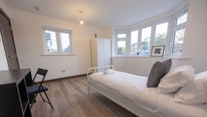 Une chambre à coucher avec un lit, un bureau, une chaise et une armoire.