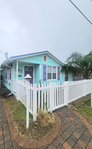 Ein Haus mit weißem Zaun, einer blauen und violetten Fassade und der Hausnummer 6880 an der Tür.