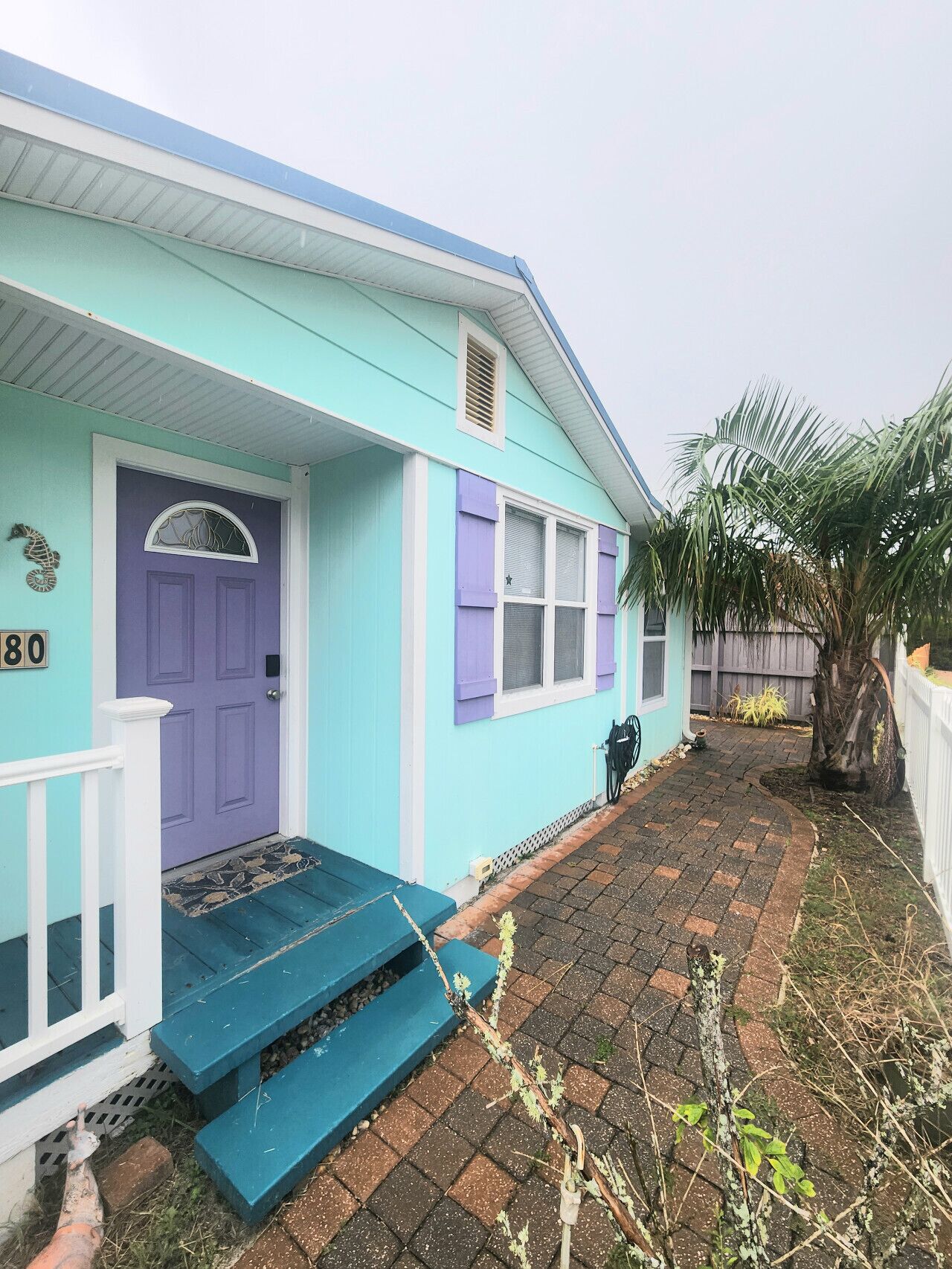 A house with a blue exterior, a purple door, and a small front porch with steps.