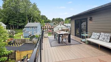 A deck with a table and chairs, a bench, and a view of houses in the background.