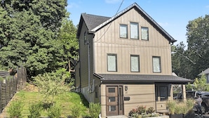 Ein zweistöckiges Haus mit Veranda, Garage und Auffahrt.