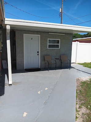 A small building with a white door, two chairs, and a window. - Villa Paris apartment#2 close to airport, hospital, stadium, market, store (Tampa)