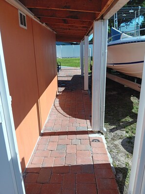 A covered outdoor corridor with a brick floor, white walls, and a view of a grassy area. - Villa Paris apartment#2 close to airport, hospital, stadium, market, store (Tampa)