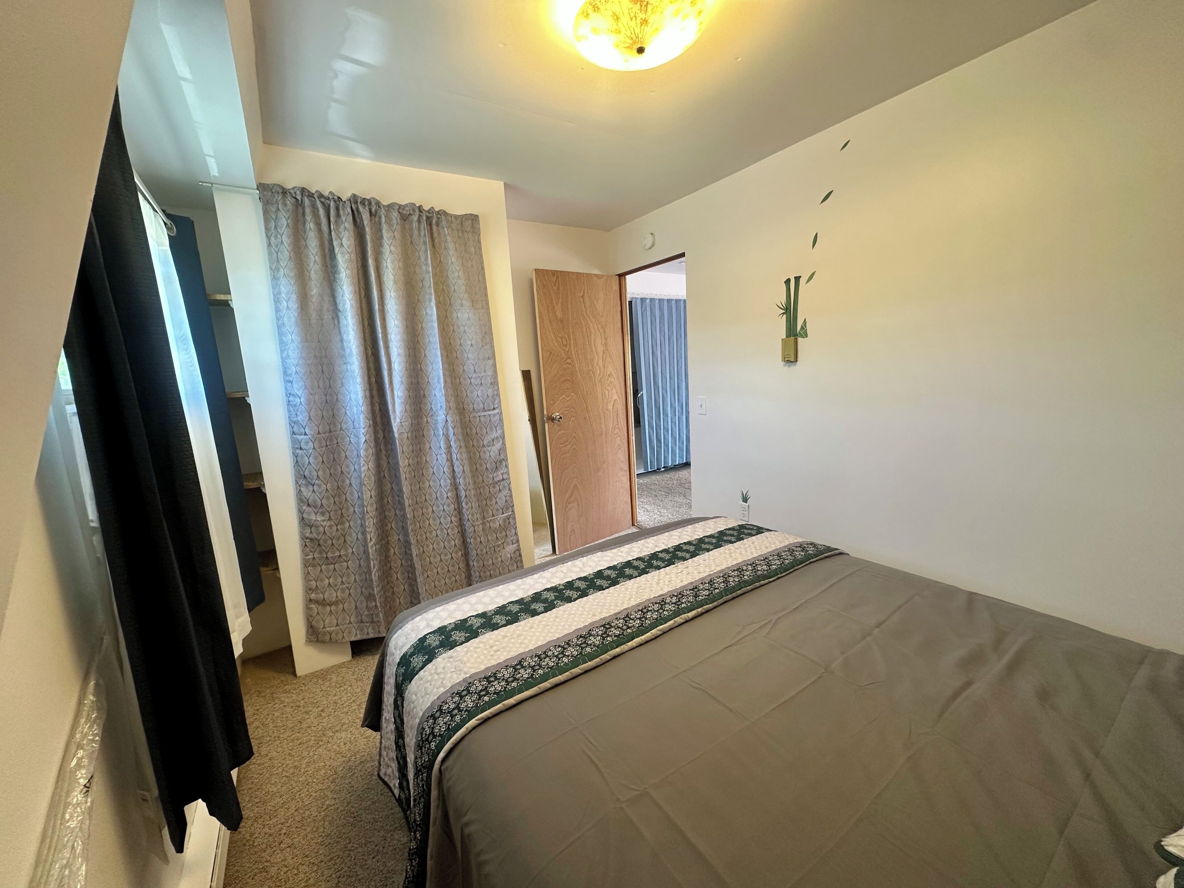 A bedroom with a bed, a wardrobe, a door, and a wall-mounted plant.