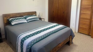 A bedroom with a bed, a nightstand, a wooden wardrobe, and a wall with a bird mural. - Rustic Barn Apartment with Mountain and Farm Views, 2-bedroom, 1-bath apartment (Apalachin)