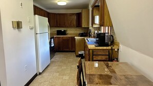 A compact kitchen with wooden cabinets, a white refrigerator, a coffee maker, and a microwave. - Rustic Barn Apartment with Mountain and Farm Views, 2-bedroom, 1-bath apartment (Apalachin)