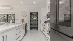 Una cocina moderna con un refrigerador de acero inoxidable, armarios blancos y un ventanal amplio.