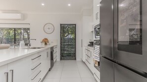 Una cocina moderna con un refrigerador de acero inoxidable, armarios blancos y un ventanal amplio.