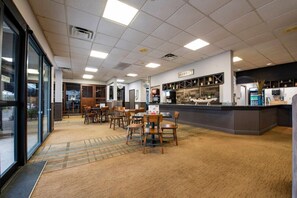 Un restaurante moderno con zona de bar, diversas opciones de asientos y un menú a la vista.