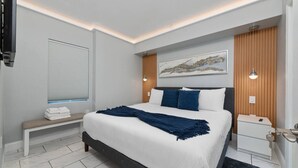 Ein modernes Schlafzimmer mit Bett, Bank, Nachttisch und Kunstwerk an der Wand.