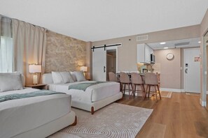 Ein Hotelzimmer mit zwei Betten, einer Essecke und einer Küchenzeile.