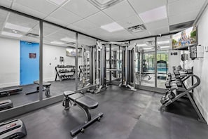 A gym with exercise equipment, a bench, and a mirror.