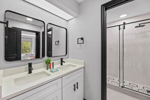 A bathroom with a double sink, a mirror, a shower, and a window. - Hawthorn Suites Suite Near Universal & I-Drive (Orlando)