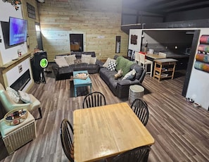 A cozy living room with a sectional sofa, a wooden coffee table, and a TV mounted on the wall.