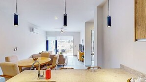 A modern kitchen with a central island, pendant lighting, and a view to a dining area. - Gorgeous Dog-friendly Apartment With Balcony, Open Layout, Heated Pool, & AC (Cabo San Lucas)