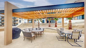 Un área de patio al aire libre con una pérgola de madera, una mesa redonda para comer y sillas.