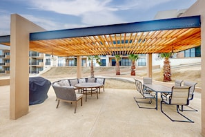 Ein Außenbereich mit einer Holzpergola, einem runden Esstisch und Stühlen.