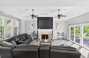 Ein Wohnzimmer mit Kamin, Deckenventilatoren und einem großen Fernseher.
