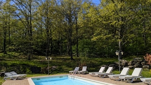A rectangular swimming pool with a brick deck, surrounded by white lounge chairs and trees in the background. - Exclusive Holiday Villa With Private Pool Between Marche and Umbria (Apecchio)