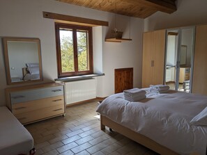 Ein Schlafzimmer mit einem Bett, einem Schminktisch, einem Spiegel, einem Fenster und einem Kleiderschrank.
