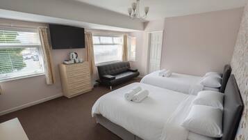 Una habitación de hotel con dos camas, televisión, sofá y cómoda.