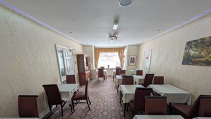 A hotel dining area with tables, chairs, patterned carpet, and a painting on the wall. - Mayfair Hotel (Skegness)