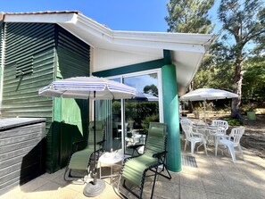 Eine Terrassenfläche mit Gartenmöbeln, darunter Stühle und Tische, sowie Sonnenschirmen als Sonnenschutz.