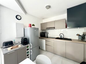 Eine moderne Küche mit Kühlschrank, Mikrowelle, Spüle und einer Uhr an der Wand.
