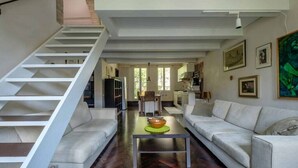 A modern living area with a staircase, a sofa, a coffee table, and a kitchen in the background. - Elegant Castello Retreat with Terrace Near Biennale & San Marco (Venezia)
