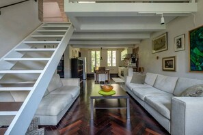 A modern living area with a staircase, a sofa, a coffee table, and a kitchen in the background. - Elegant Castello Retreat with Terrace Near Biennale & San Marco (Venezia)