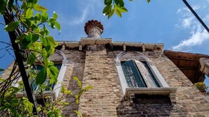 A historic building with a stone facade, arched windows, and a chimney. - Elegant Castello Retreat with Terrace Near Biennale & San Marco (Venezia)