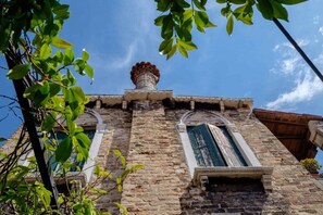A historic building with a stone facade, arched windows, and a chimney. - Elegant Castello Retreat with Terrace Near Biennale & San Marco (Venezia)