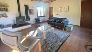 A spacious living room with a sofa, armchair, and a fireplace. - Peaceful Holiday House with Private Pool and Panoramic Views: Casa Mumu (Casteletto D’Erro)