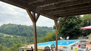 An outdoor dining area with a view of a swimming pool and hills. - Peaceful Holiday House with Private Pool and Panoramic Views: Casa Mumu (Casteletto D’Erro)
